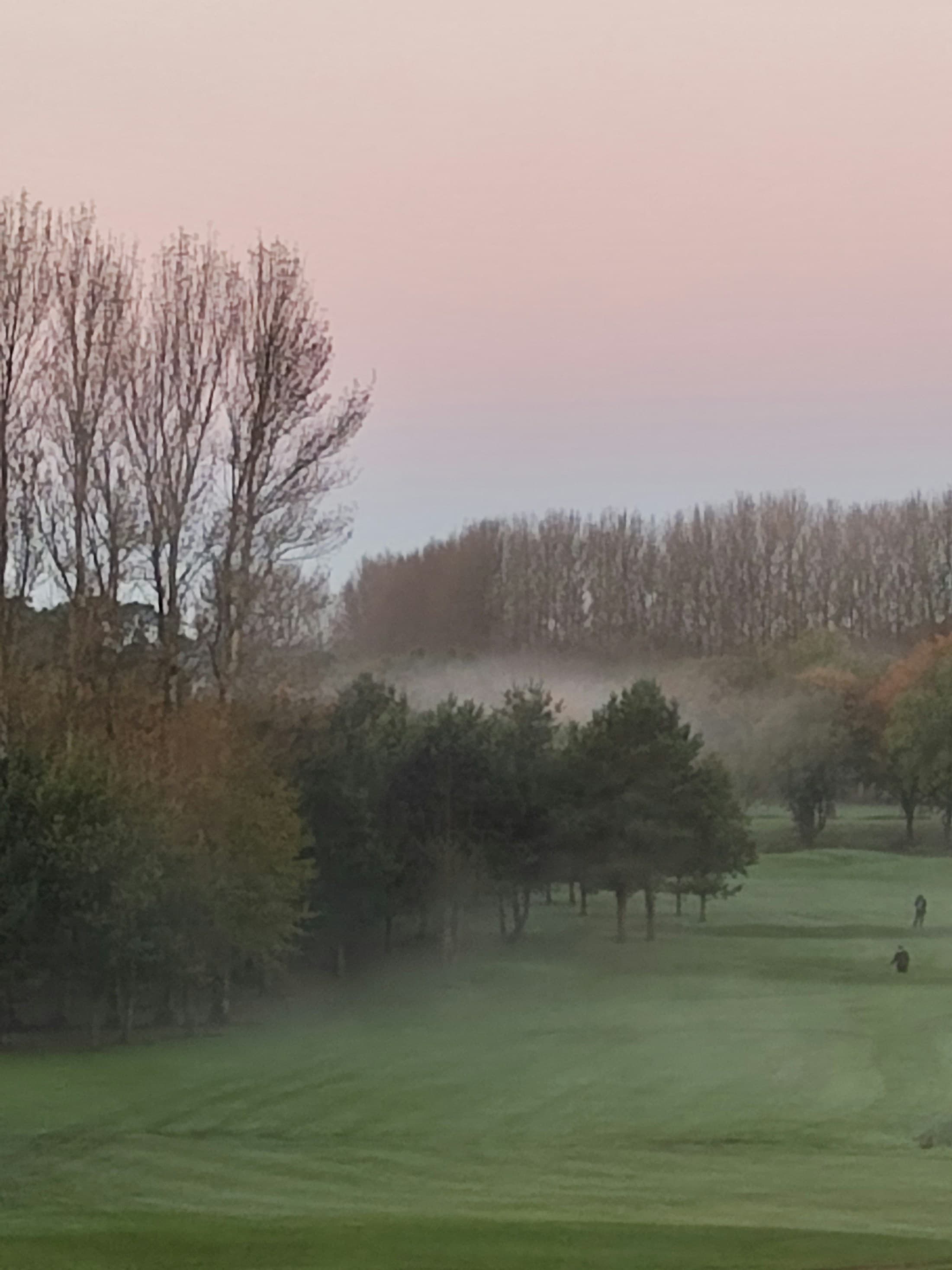Fog lifting over a golf course fairway